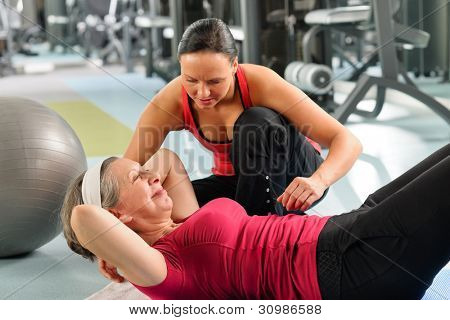 Picture or Photo of Fitness center senior woman exercise with personal trainer on mat