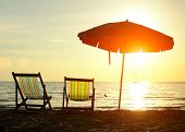 stock photo of holidays  - Pair of beach loungers on the deserted coast sea at sunrise - JPG 