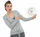 stock photo of time  - Shocked business woman pointing on clock isolated on white - JPG 