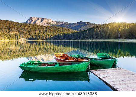 Picture or Photo of Reflection in water of mountain lakes and boats. Black lake in Durmitor national park in Montenegro, Europe. Beauty world.