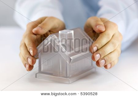 Picture or Photo of Hands covering a glass model home over white background