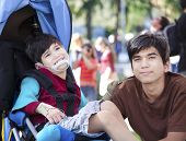 pic of cerebral  - Big brother taking care of disabled little boy in wheelchair outdoors - JPG 