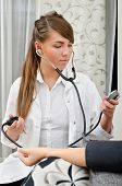 image of pressure  - Female doctor with stethoscope measures patient - JPG 