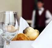 stock photo of restaurant  - table setting in restaurant with bread empty glass and waiter off focus - JPG 