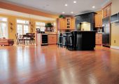 picture of interior  - Home interior shows a large expanse of wood flooring in the foreground and a kitchen and dining room in the background - JPG 